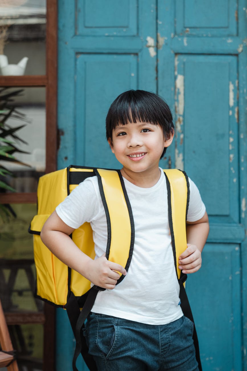 happy ethnic boy carrying food backpack