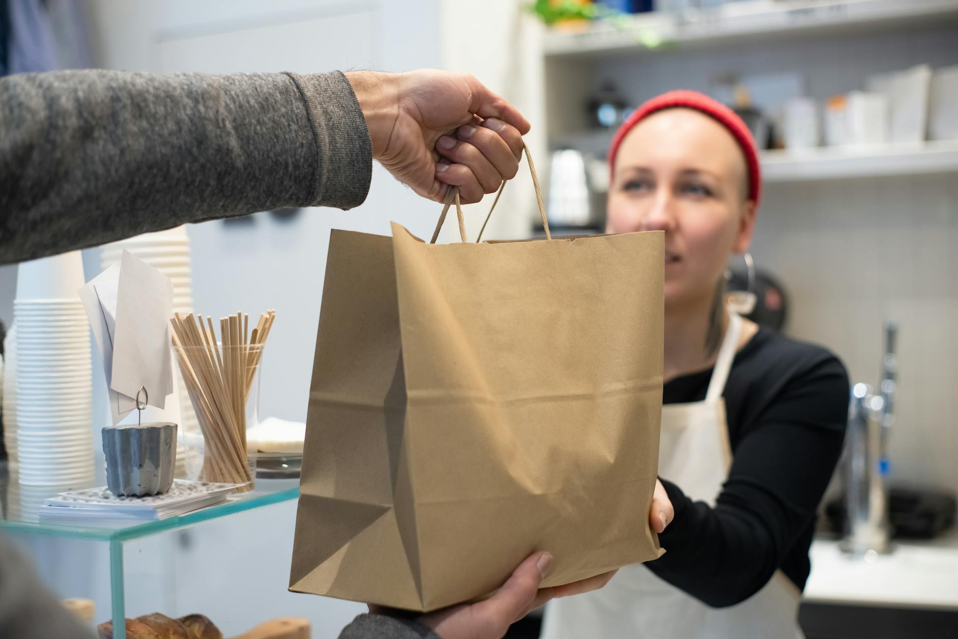 close up of restaurant worker handing a bag with takeaway food to a client